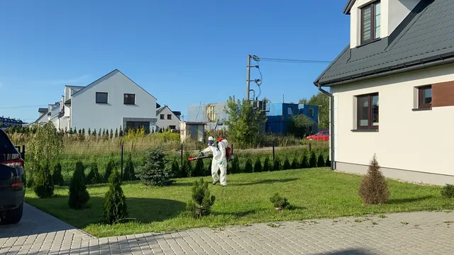 Odkomarzanie posesji — technik ze sprzętem ULV na trawniku