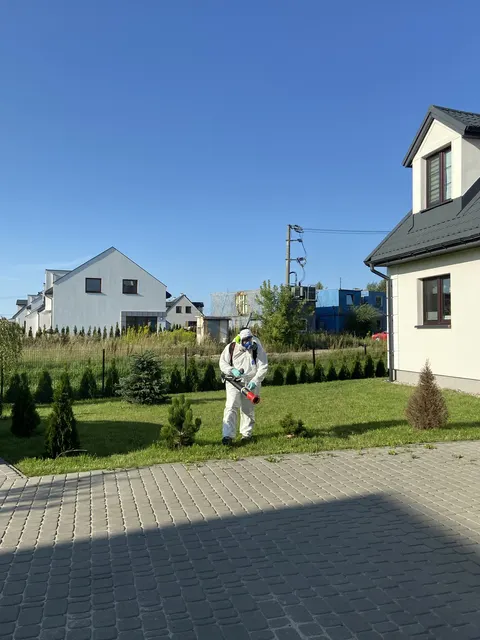 Technik podczas zabiegu widoczny w tle ogrodu